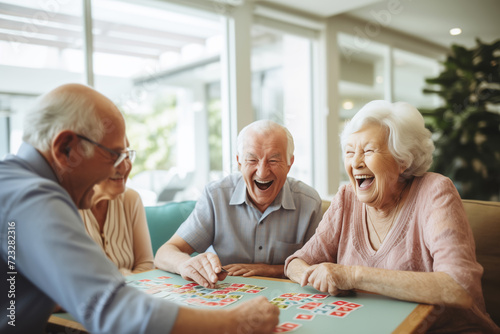 Three seniors laugh heartily during board game in geriatric clinic or nursing home