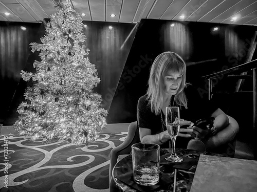 A woman checking her phone by th elight of a Christmas tree photo