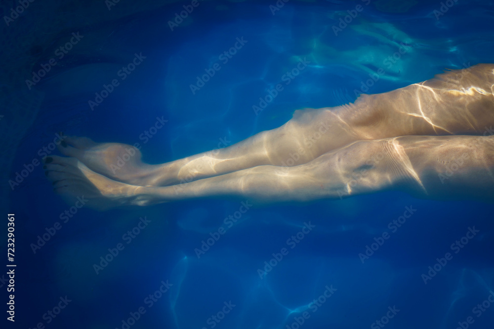 Fototapeta premium The legs of a young woman in a swimming pool