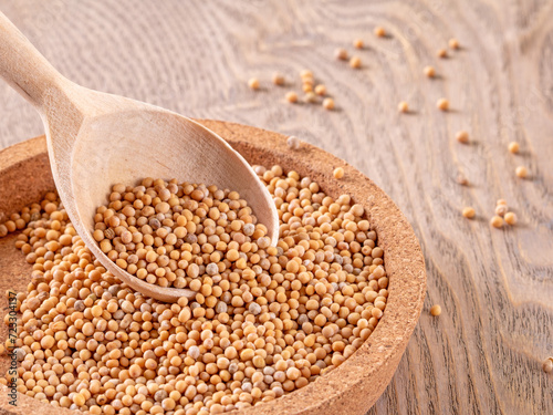 Mustard seeds in close proximity: wooden spoon filled with mustard seeds, culinary ingredient photo