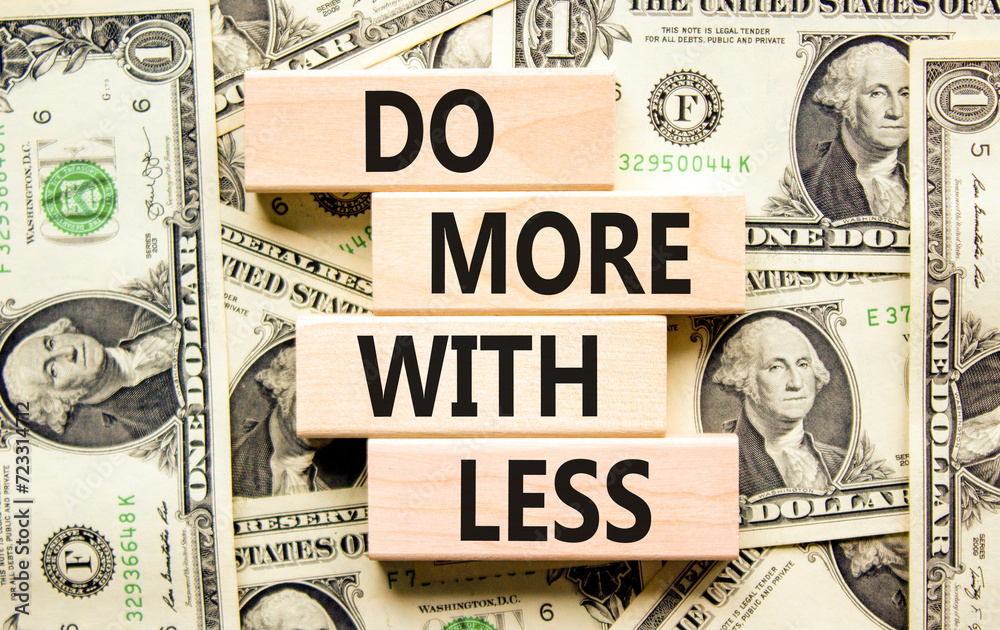 Do more with less symbol. Concept word Do more with less on beautiful wooden block. Dollar bills. Beautiful background from dollar bills. Business do more with less concept. Copy space.