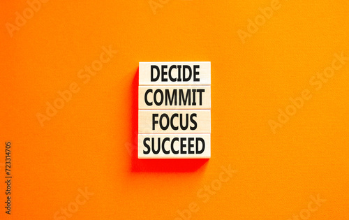 Decide commit focus succeed symbol. Concept word Decide Commit Focus Succeed on wooden block. Beautiful orange table orange background. Business decide commit focus succeed concept. Copy space.