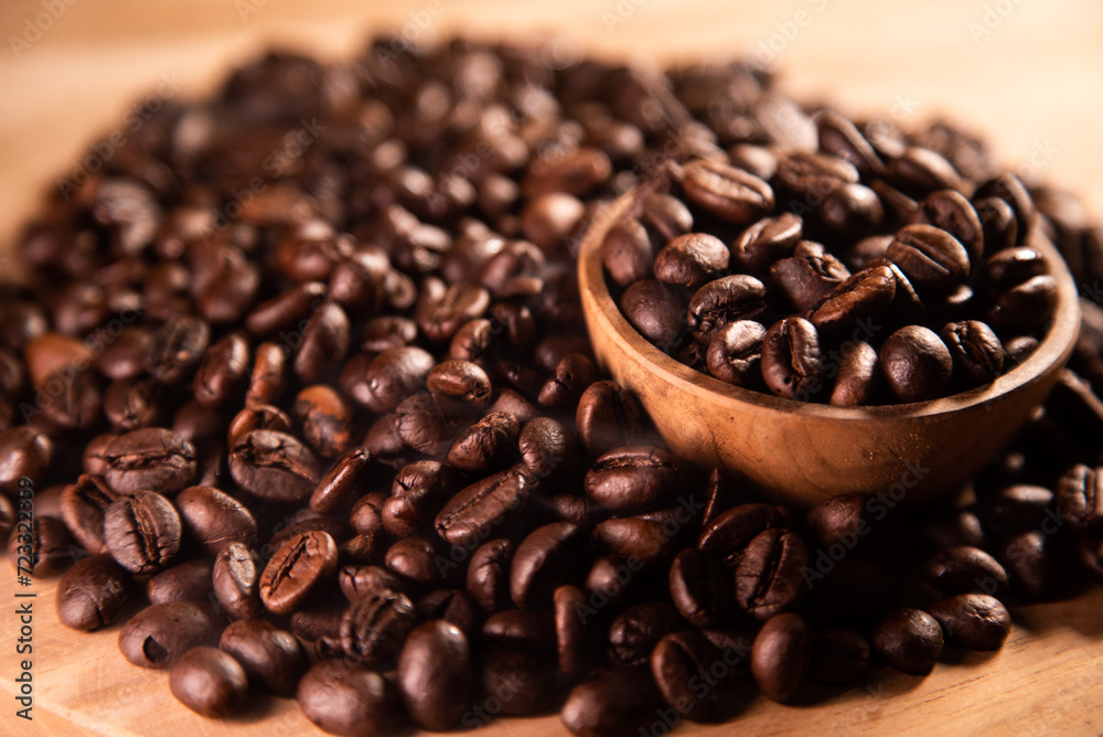 Fototapeta premium Roasted coffee beans on a wooden board. Coffee beans in a small wooden bowl. Concept for commercial product