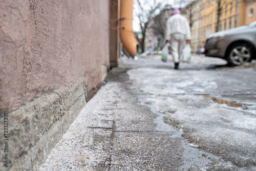 Selective focus on technical salt grains on icy sidewalk surface in wintertime, used for melting ice and snow. Applying salt to keep roads clear and people safe in winter weather from ice or snow © DimaBerlin