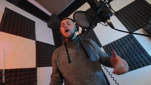 Musician Recording Vocals in Soundproof Studio, ale artist singing into microphone with pop filter in acoustically treated recording studio. photo