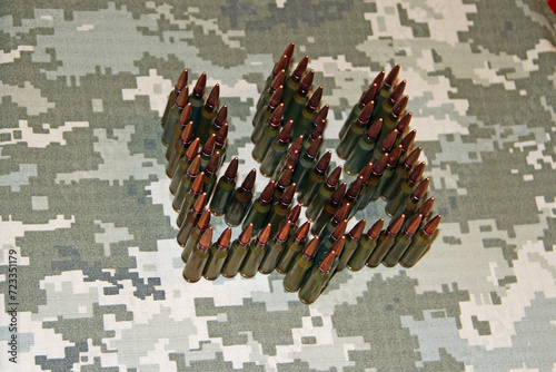 coat of arms of Ukraine laid out from cartridges on camouflage clothing photo