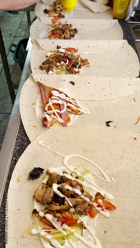 Fast food chef pours sauce from a bottle onto shawarma ingredients.