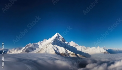 majestic snowy mountain peak towering above the clouds its pristine white slopes contrasting against the deep blue sky  © Slainie