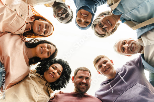 Group portrait of smiling multiracial business people looking at camera hugging standing in circle. Confident workers, colleagues in modern office. Meeting. Successful business, career, startup team   © Maria Vitkovska