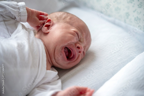 Fotografie Close up portrait of crying newborn baby in the bed