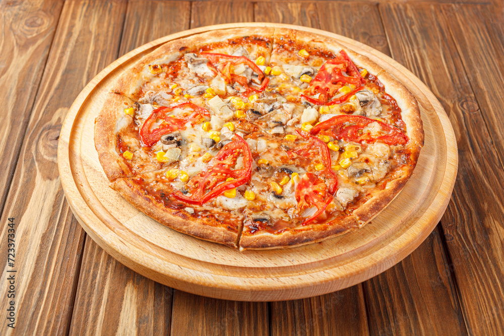 delicious pizza with chicken, mushrooms, cheese, tomatoes and corn on a wooden background delicious pizza with chicken, mushrooms, cheese, tomatoes and corn on a wooden background