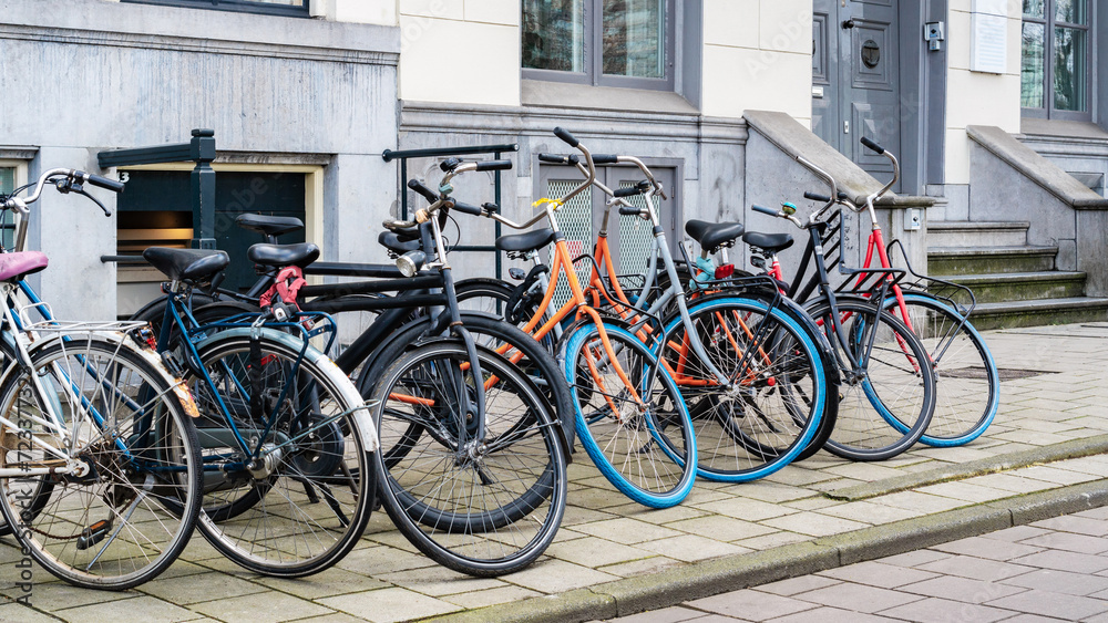 Bike parking in the city. Bicycle parking along a street near a city building in Amsterdam. An urban cityscape with bicycles. Walking bikes parked casually along an old street in Netherlands. Bike parking in the city. Bicycle parking along a street near a city building in Amsterdam. An urban cityscape with bicycles. Walking bikes parked casually along an old street in Netherlands.