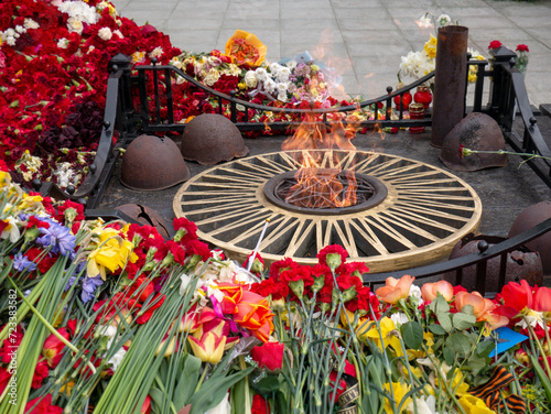 Eternal flame on a background of flowers on Victory Day on May 9, Victory Day at the memorial to the unknown soldier. Eternal flame in memory of those who died in the war