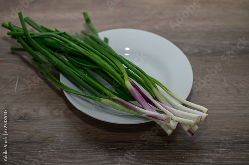 young green onions on a plate on a wooden table 1