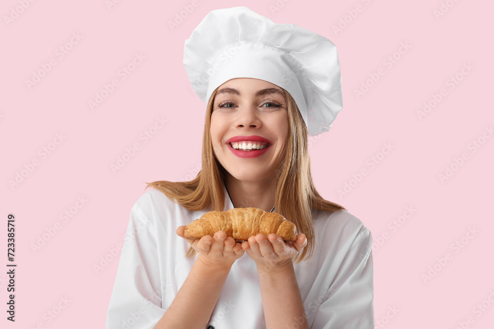 Young female chef with croissant on pink background Young female chef with croissant on pink background
