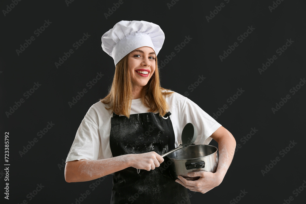 Young female chef with ladle and cooking pot on black background Young female chef with ladle and cooking pot on black background