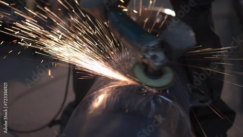 Sparks during pipe grinding at the factory by a worker