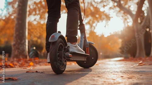 Close up of man riding black electric kick scooter at beautiful park landscape