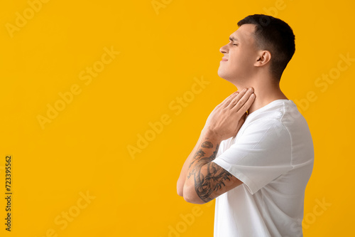 Young man with thyroid gland problem on yellow background photo