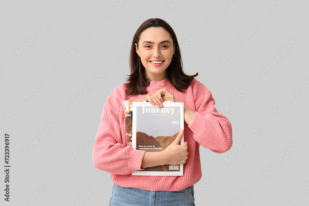 Smiling young woman with magazines on light background Smiling young woman with magazines on light background