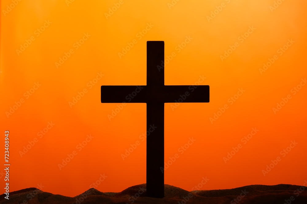 Wooden cross on sand against orange background. Good Friday concept Wooden cross on sand against orange background. Good Friday concept