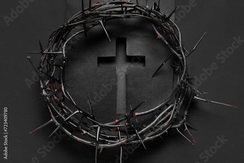 Cut black paper in shape of cross with crown of thorns on dark background. Good Friday concept