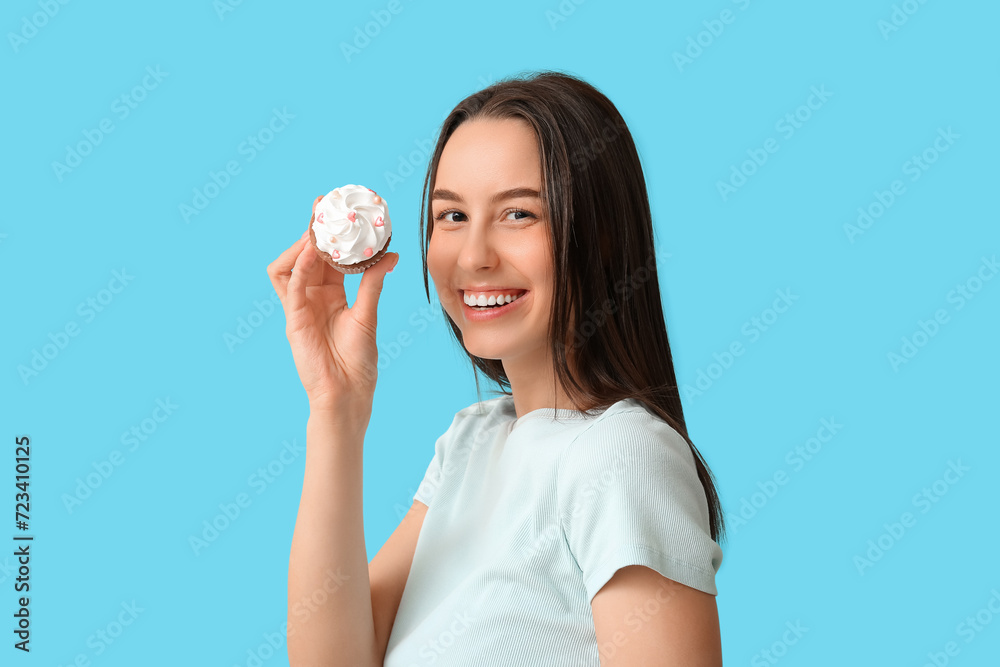 Young woman with sweet cupcake on blue background. Valentine's Day celebration