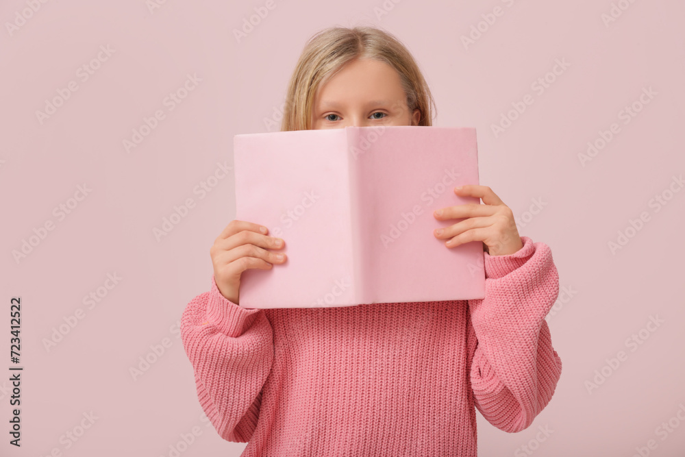 Cute little girl with book on pink background Cute little girl with book on pink background