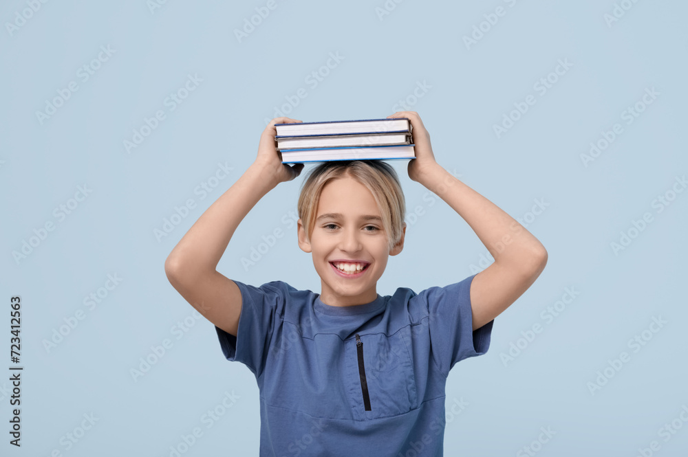 Cute little boy with books on blue background Cute little boy with books on blue background