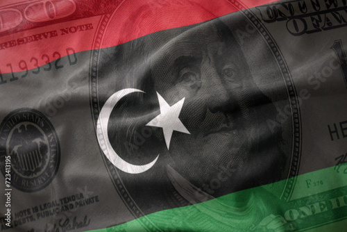 waving colorful flag of libya on a american dollar money background. finance concept.
