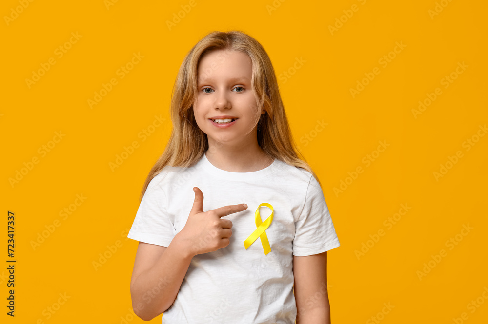 Teenage girl pointing at yellow ribbon on color background. International Childhood Cancer Day Teenage girl pointing at yellow ribbon on color background. International Childhood Cancer Day