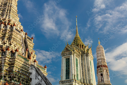 Intricately decorated temple and prangs at Wat Arun (Temple of the Dawn), Bangkok, Thailand. Blue sky and clouds in the background. 