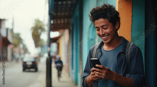 Happy smiling young man is using a smartphone outdoors photo