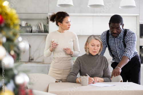 Couple man and woman discussing testament with elderly woman in kitchen at home