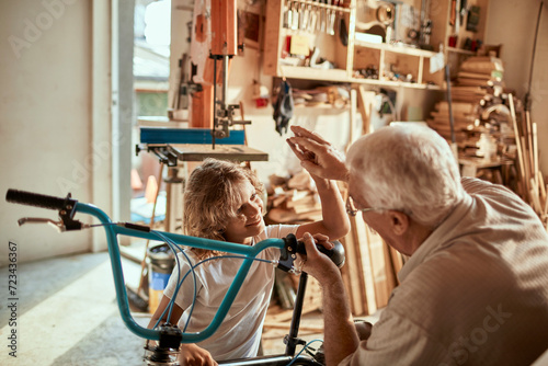 Grandfather and grandson working on a bicycle in the garage photo