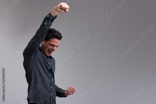 Young man celebrates, arms up, masculine photo