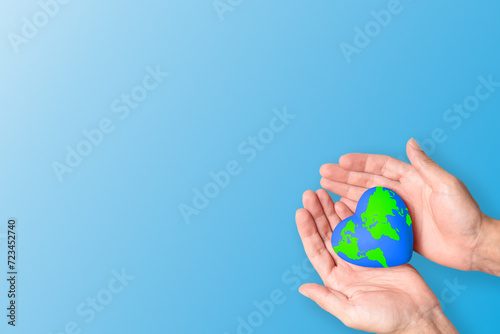 Delicate hands cradle the Earth in a heart shape, symbolizing the call to cherish and protect our planet. Ideal for Earth Day and environmental conservation campaigns, with  blue background.
