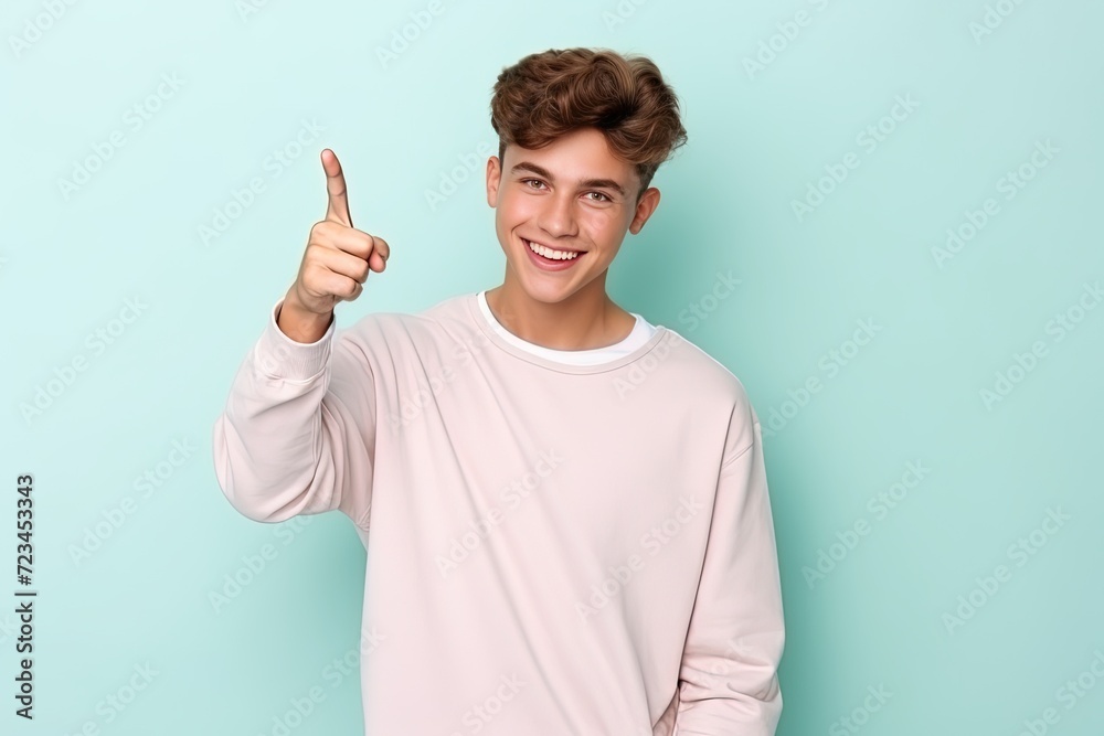 A good looking guy with a finger pointing upward on a pastel color background A good looking guy with a finger pointing upward on a pastel color background