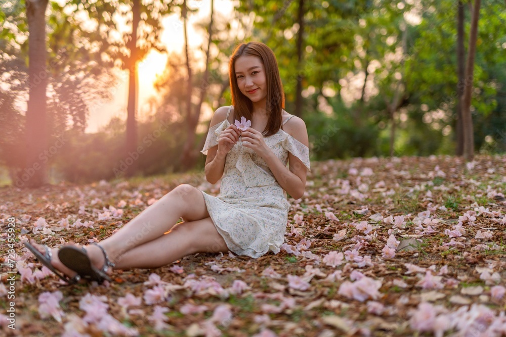 Young Asian beauty enjoys playing and posing with sakura flowers at a public park during sunset moments Young Asian beauty enjoys playing and posing with sakura flowers at a public park during sunset moments