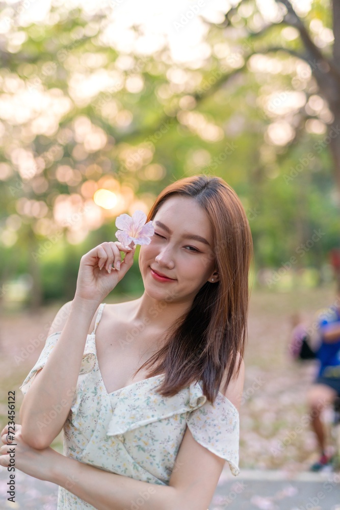 Beautiful young asian woman enjoying nature during sunset moments at a public park with lots of sakura flowers Beautiful young asian woman enjoying nature during sunset moments at a public park with lots of sakura flowers