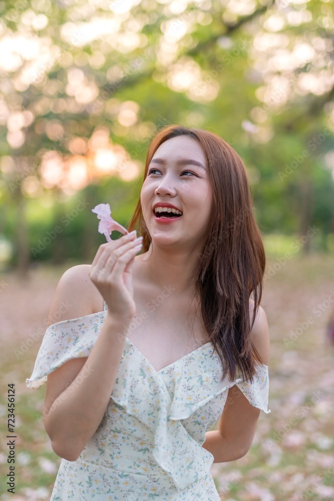 Beautiful young asian woman enjoying nature during sunset moments at a public park with lots of sakura flowers Beautiful young asian woman enjoying nature during sunset moments at a public park with lots of sakura flowers