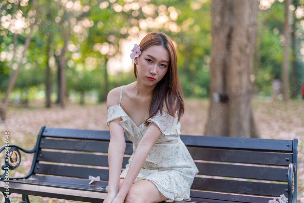 Beautiful young asian woman enjoying outdoor breeze during sunset moments at a public park with lots of sakura flowers Beautiful young asian woman enjoying outdoor breeze during sunset moments at a public park with lots of sakura flowers