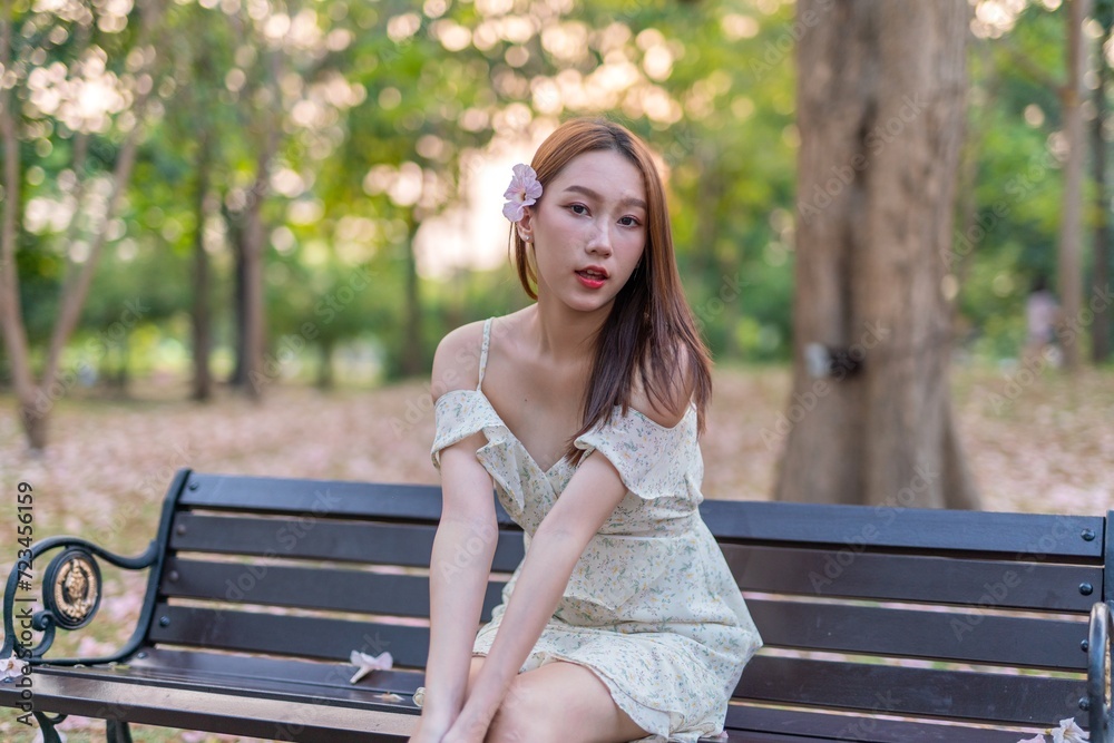 Beautiful young asian woman enjoying outdoor breeze during sunset moments at a public park with lots of sakura flowers Beautiful young asian woman enjoying outdoor breeze during sunset moments at a public park with lots of sakura flowers