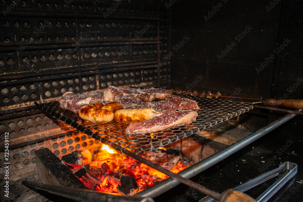 Churrasco brasileiro com grellha assando picanha e pão de alho ainda espeto com coração de frango.