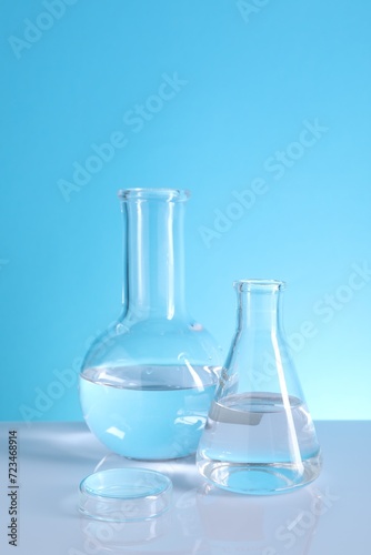Laboratory analysis. Glass flasks on table against light blue background