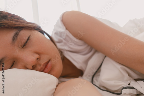 Close up of lazy Asian woman just wake up but not going to get up from the bed.