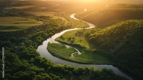 Aerial view of a meandering river through a lush, green valley at sunset