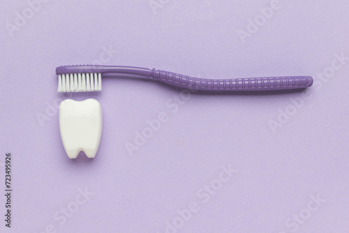 A purple brush cleaning a white tooth figurine on a purple background.