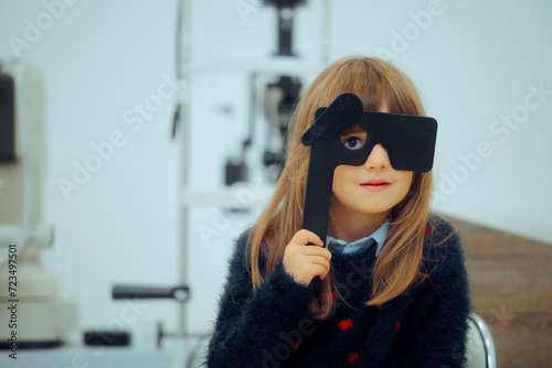 Little Patient Girl Holding a Lorgnette Pinhole occluder for Consultation photo