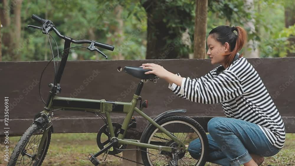 Chilling and relaxed young Asian woman in casual comfy clothes riding a bicycle on the bike lane in the park. hobby and exercise concept Chilling and relaxed young Asian woman in casual comfy clothes riding a bicycle on the bike lane in the park. hobby and exercise concept